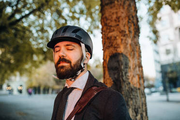 Geschäftsmann mit Helm in der Stadt bei Sonnenuntergang, Augen geschlossen, Raum kopieren. - HPIF27831