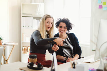 Gruppe junger glücklicher Geschäftsfrauen mit Smartphone im Gespräch in einem modernen Büro. - HPIF27850