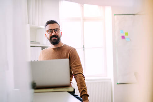 Reifer Hipster-Geschäftsmann mit Laptop, der in einem modernen Büro arbeitet, Kopierraum. - HPIF27852