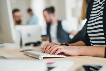 Group of young, male and female businesspeople with computer working together in a modern office, a midsection view. - HPIF27863