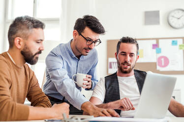 Group of young cheerful businessmen with laptop working in a modern office. - HPIF27869