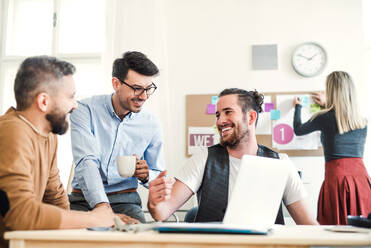 Group of young, cheerful, male and female businesspeople with laptop working together in a modern office. - HPIF27870