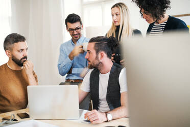 Eine Gruppe junger, konzentrierter männlicher und weiblicher Geschäftsleute mit Laptop trifft sich in einem modernen Büro. - HPIF27876