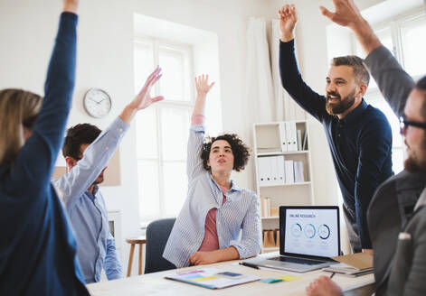 Eine Gruppe junger Geschäftsleute sitzt in einem modernen Büro am Tisch und feiert ihren Erfolg. - HPIF27932