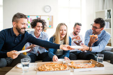 Eine Gruppe von jungen Geschäftsleuten mit Pizza beim Mittagessen in einem modernen Büro. - HPIF27947