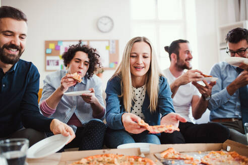 Eine Gruppe von jungen Geschäftsleuten mit Pizza beim Mittagessen in einem modernen Büro. - HPIF27948