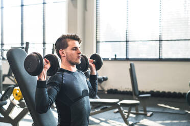 Junge, fitte Männer machen Krafttraining, trainieren mit Hanteln in einem modernen Fitnessstudio. Raum kopieren. - HPIF27956