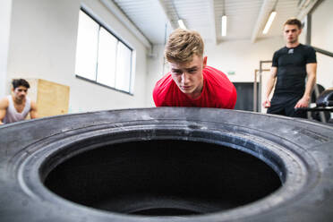Fit junger Mann mit seinen Freunden in der Turnhalle trainieren, bewegen großen Reifen. - HPIF27988
