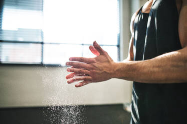 Ein fitter junger Bodybuilder schmiert sich im Fitnessstudio die Hände mit Magnesium ein, Nahaufnahme, Raum kopieren. - HPIF28008