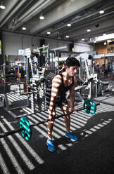 Junger, gut aussehender, fitter Mann im Fitnessstudio, der trainiert, eine Hantelstange hebt und Muskeln anspannt. - HPIF28011