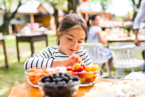 Familienfeier im Hinterhof, kleines Mädchen am Tisch stehend. - HPIF28056