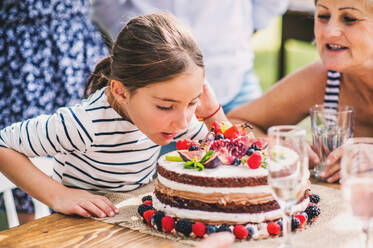 Familienfeier im Garten, große Gartenparty, Geburtstagsparty, kleines Mädchen mit Geburtstagstorte. - HPIF28090