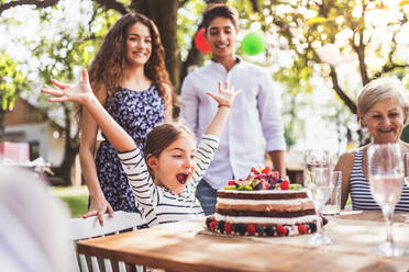 Familienfeier im Garten, große Gartenparty, Geburtstagsparty, kleines Mädchen mit Geburtstagstorte. - HPIF28091