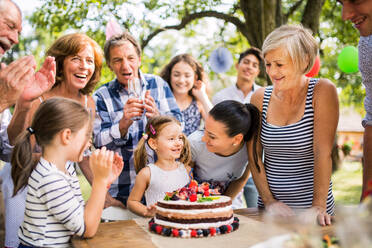 Familienfeier im Hinterhof, großer Garten oder Geburtstagsfeier, kleines Mädchen mit Torte. - HPIF28099