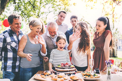 Familienfeier im Garten, große Gartenparty, Geburtstagsparty, kleines Mädchen mit Geburtstagstorte. - HPIF28100