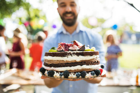Familienfeier im Hinterhof, großer Garten oder Geburtstagsfeier, reifer Mann mit Geburtstagstorte. - HPIF28108