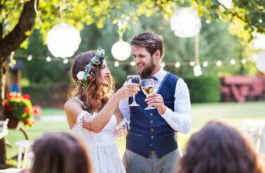 Hochzeitsempfang im Hinterhof, Braut und Bräutigam stoßen mit Gläsern an. - HPIF28123