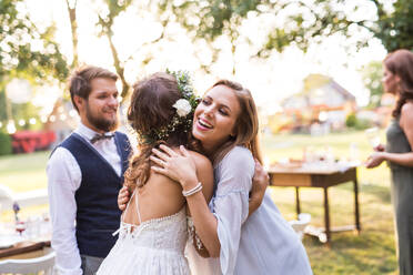 Junges Mädchen gratuliert Braut und Bräutigam bei der Hochzeitsfeier draußen im Hinterhof. - HPIF28126