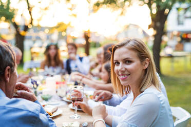 Wedding reception outside in the backyard. Bride, groom and the guests sitting at the table. - HPIF28140