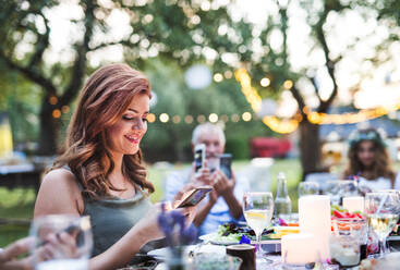 Gäste mit Smartphones fotografieren bei der Hochzeitsfeier im Hinterhof. - HPIF28144