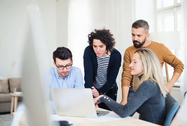 Eine Gruppe junger, fröhlicher Geschäftsleute mit Laptop arbeitet in einem modernen Büro zusammen. - HPIF28152