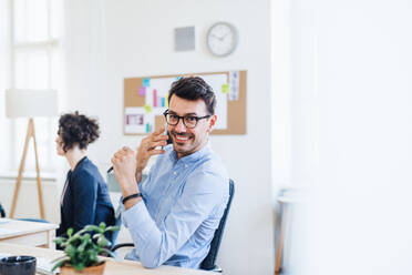 Young businessman with smartphone working in a modern office, making a phone call. - HPIF28173