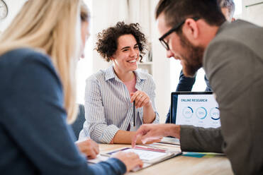 Group of young, cheerful, male and female businesspeople with laptop working together in a modern office. - HPIF28182