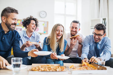 Eine Gruppe von jungen Geschäftsleuten mit Pizza beim Mittagessen in einem modernen Büro. - HPIF28186