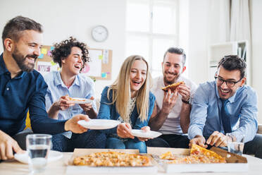Group of young male and female businesspeople with pizza having lunch in a modern office. - HPIF28186