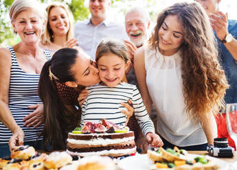 Familienfeier im Garten, große Gartenparty, Geburtstagsparty, kleines Mädchen mit Geburtstagstorte. - HPIF28204