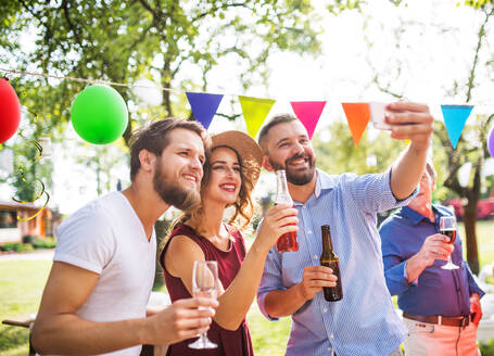 Eine Gruppe fröhlicher Jugendlicher, die mit einem Selfie auf der Party im Hinterhof Erinnerungen festhält - HPIF28211