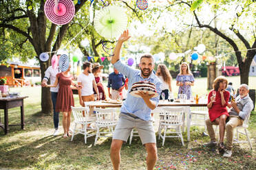 Familienfeier im Hinterhof, großer Garten oder Geburtstagsparty, reifer Mann mit Geburtstagstorte. - HPIF28229