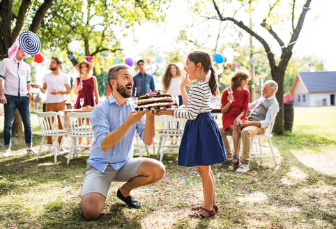 Familienfeier im Hinterhof, Vater gibt einem kleinen Mädchen einen Kuchen zum Geburtstag. - HPIF28230