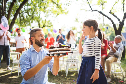 Familienfeier im Hinterhof, Vater gibt einem kleinen Mädchen einen Kuchen zum Geburtstag. - HPIF28231