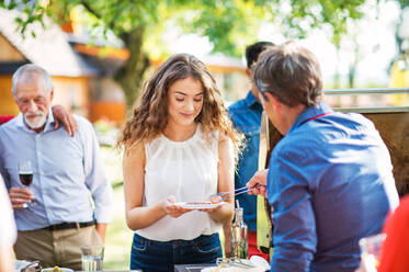 Familienfeier im Hinterhof, Grillparty, ein alter Mann kocht und serviert Essen. - HPIF28235