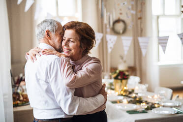 Ein Porträt eines älteren Paares, das sich in einem für eine Party eingerichteten Raum umarmt. - HPIF28283