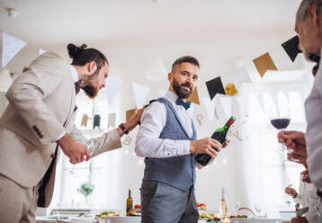 Ein Mann schenkt glücklichen Gästen auf einer Indoor-Familiengeburtstagsfeier Wein ein. - HPIF28287