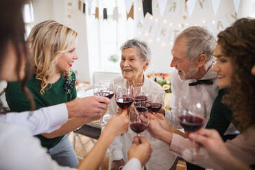 Eine Mehr-Generationen-Familie stößt auf einem Familiengeburtstag im Haus mit Rotwein an. - HPIF28290