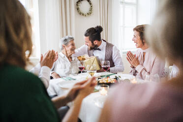 Eine ältere Großmutter feiert ihren Geburtstag mit der Familie und erhält ein Geschenkpaket, ein Partykonzept. - HPIF28293