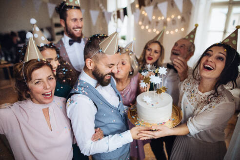 Ein Porträt einer Mehrgenerationenfamilie mit Kuchen und Partyhüten auf einer Indoor-Geburtstagsfeier. - HPIF28301