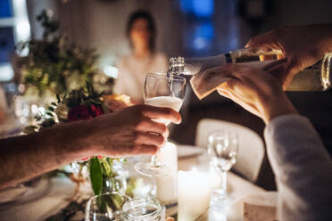 Ein unauffälliger Kellner gießt auf einer nächtlichen Party Champagner in ein Glas. - HPIF28308