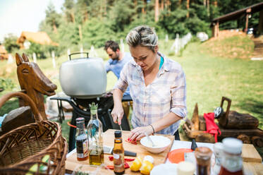 Ein Paar, das im Hinterhof auf einem Grill Essen zubereitet. Eine Gartenparty. - HPIF28316