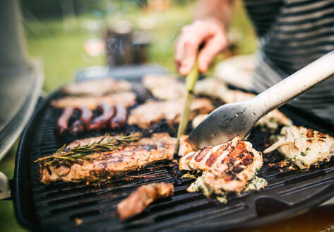 Unbekannter Mann, der an einem sonnigen Tag im Hinterhof Meeresfrüchte auf einem Grill zubereitet, Nahaufnahme. - HPIF28319