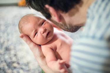 Unbekannter Vater, der ein neugeborenes Baby zu Hause im Arm hält, Kopierraum. - HPIF28341