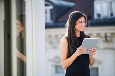 Junge Geschäftsfrau mit Tablet, die auf einer Terrasse vor einem Büro in der Stadt steht, Raum kopieren. - HPIF28379