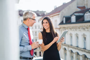 Man and woman business partners with tablet standing on a terrace in office in city, talking. - HPIF28384