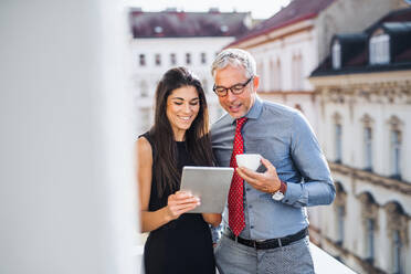 Man and woman business partners with tablet standing on a terrace in office in city, talking. - HPIF28387