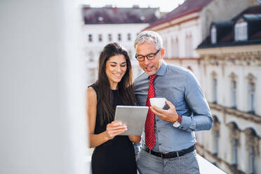 Mann und Frau Geschäftspartner mit Tablet stehen auf einer Terrasse im Büro in der Stadt, im Gespräch. - HPIF28387