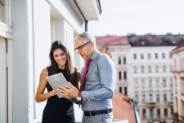 Mann und Frau Geschäftspartner mit Tablet stehen auf einer Terrasse im Büro in der Stadt, im Gespräch. - HPIF28388