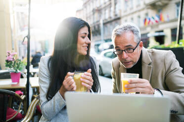 Mann und Frau Geschäftspartner mit Laptop und Getränke sitzen in einem Café in der Stadt, im Gespräch. - HPIF28406